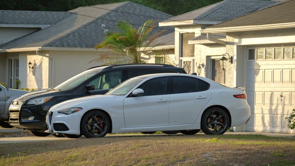 Cars parked in front of wide garage double door on concrete driveway of new modern american house. Sarasota, USA - May 2, 2022.