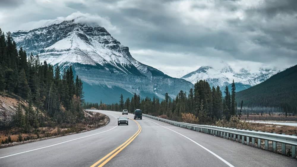 Road trip with car driving among rocky mountains in the forest on gloomy at Banff national park, Alberta, Canada