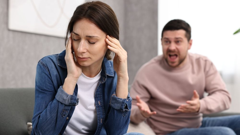 Offended wife ignoring her angry husband indoors, selective focus. Relationship problems