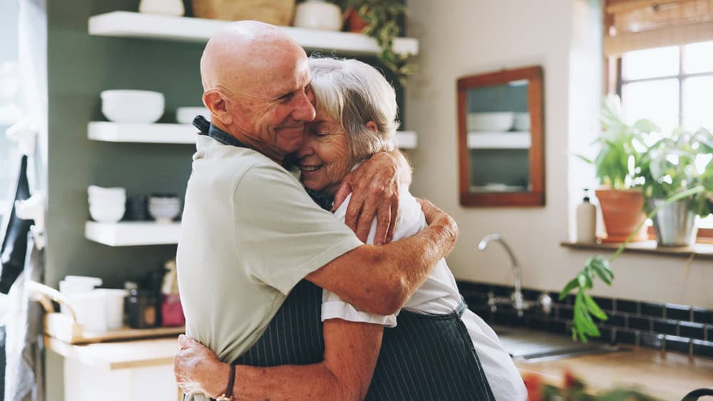 Kitchen, hug and senior couple in home for love, bonding relationship and commitment together. Marriage, happy and elderly man and woman cooking together for wellness, meal prep and health in house