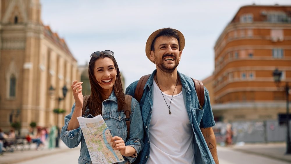 Happy couple walking through the town during their summer travel. Copy space.