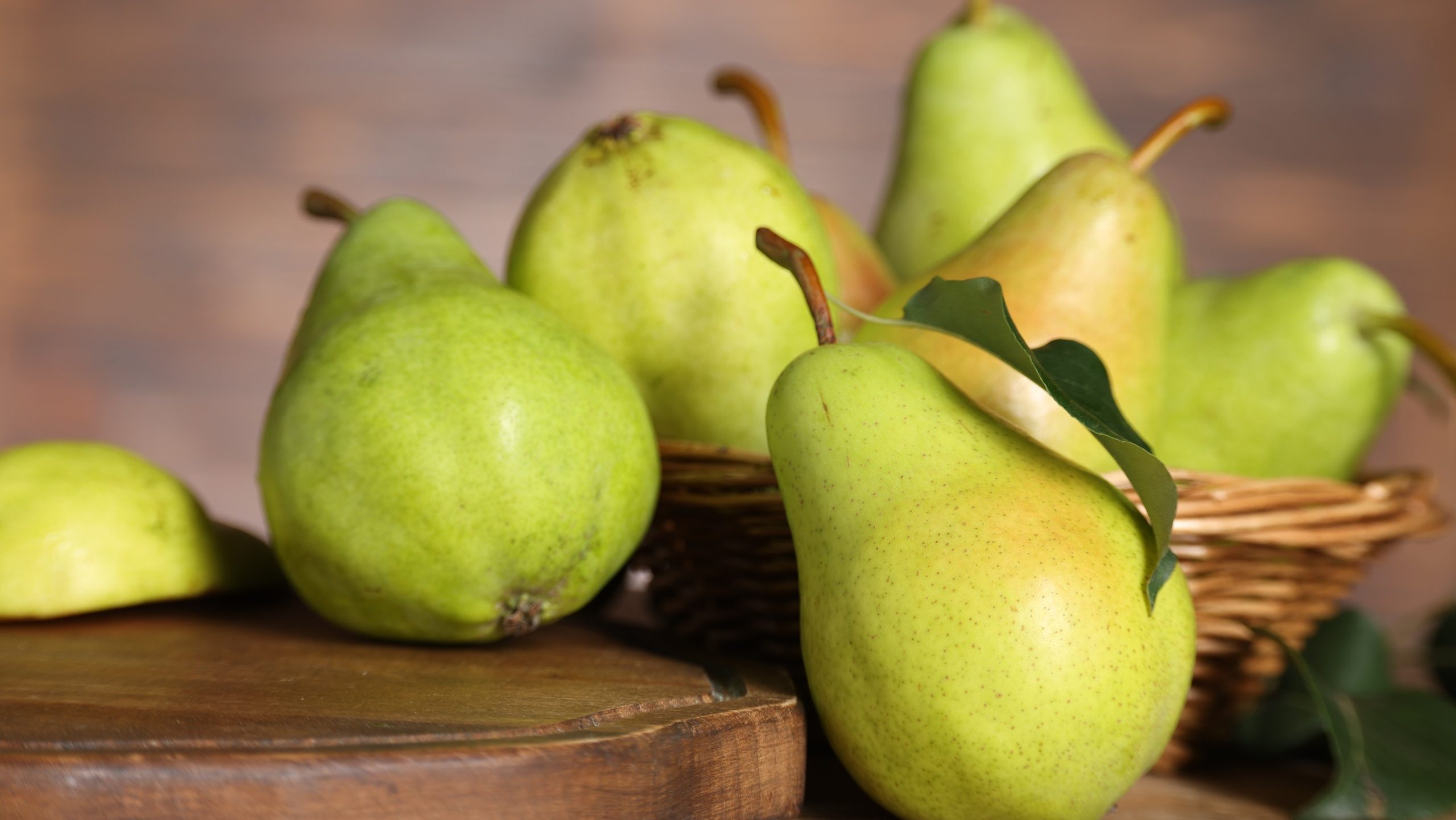 Fresh green pears and leaf on wooden table, closeup