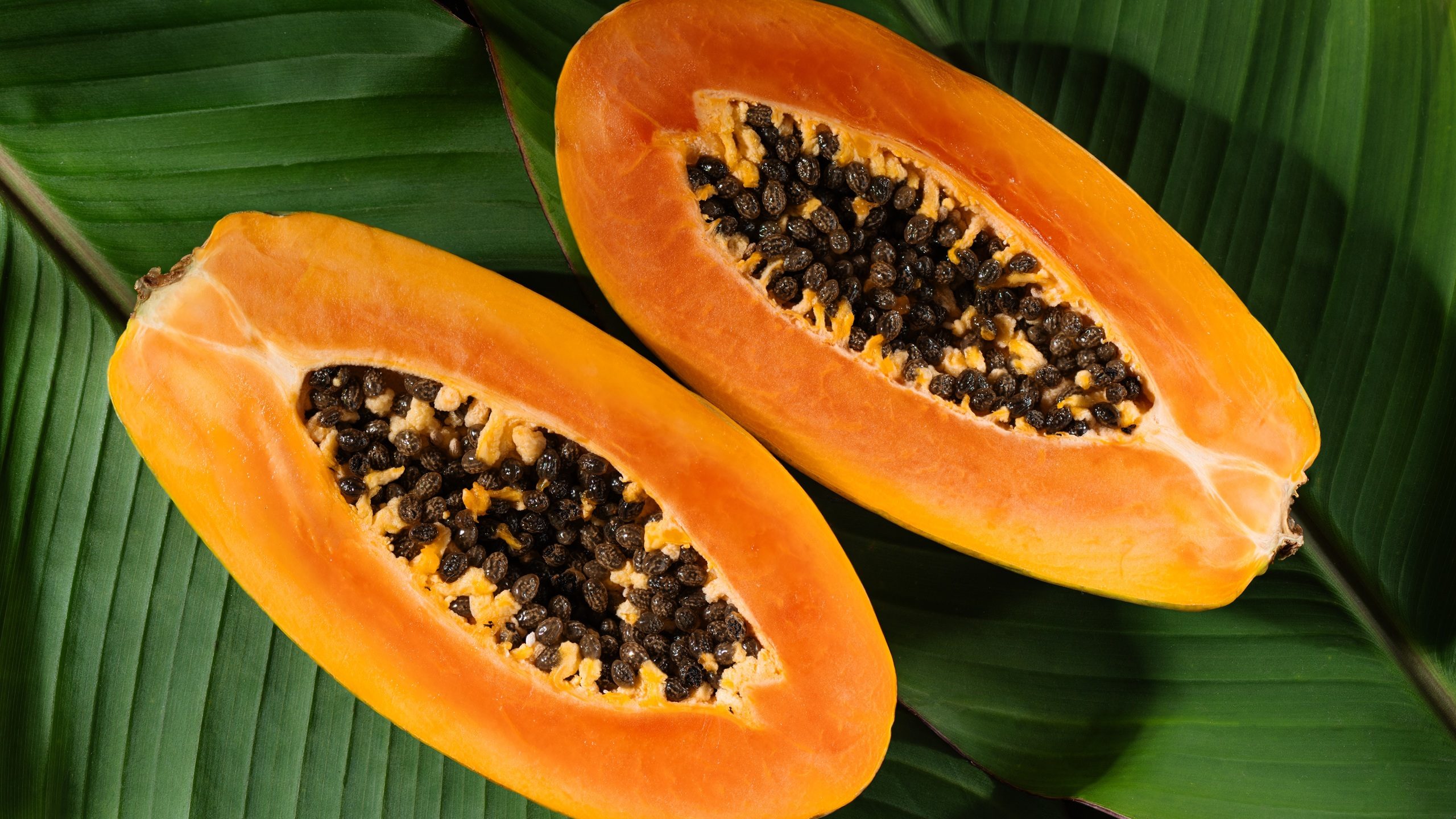 Juicy papaya fruit cut in half, with seeds and bright orange flesh top view. This photo highlights the freshness and nutritional value of papaya fruit, ideal for healthy food background.
