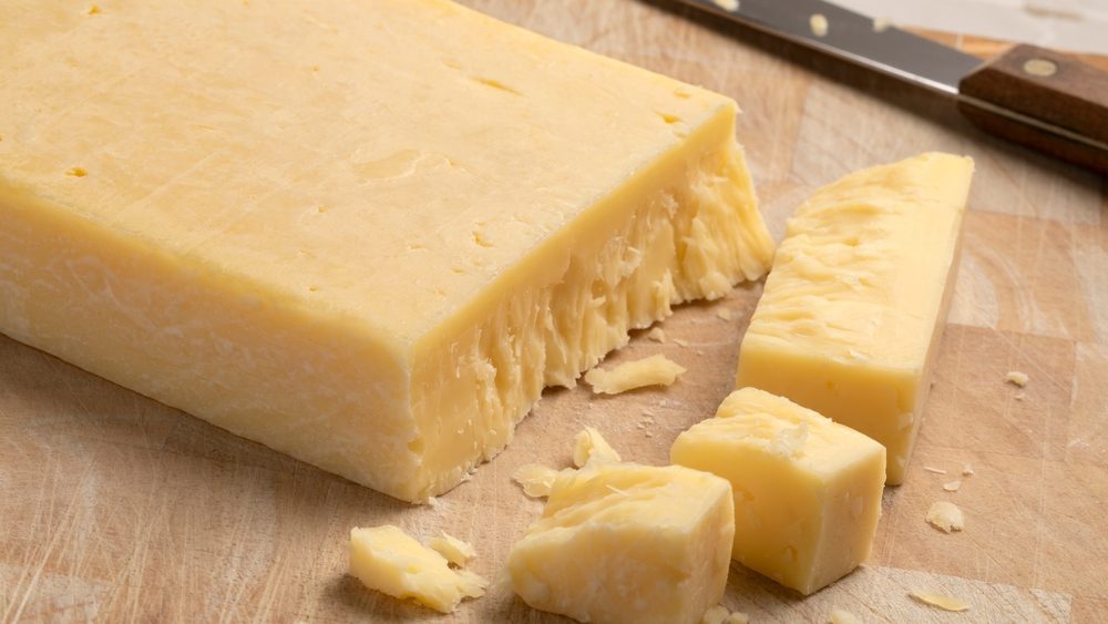 Extra mature english traditional cheddar cheese and pieces on a cutting board