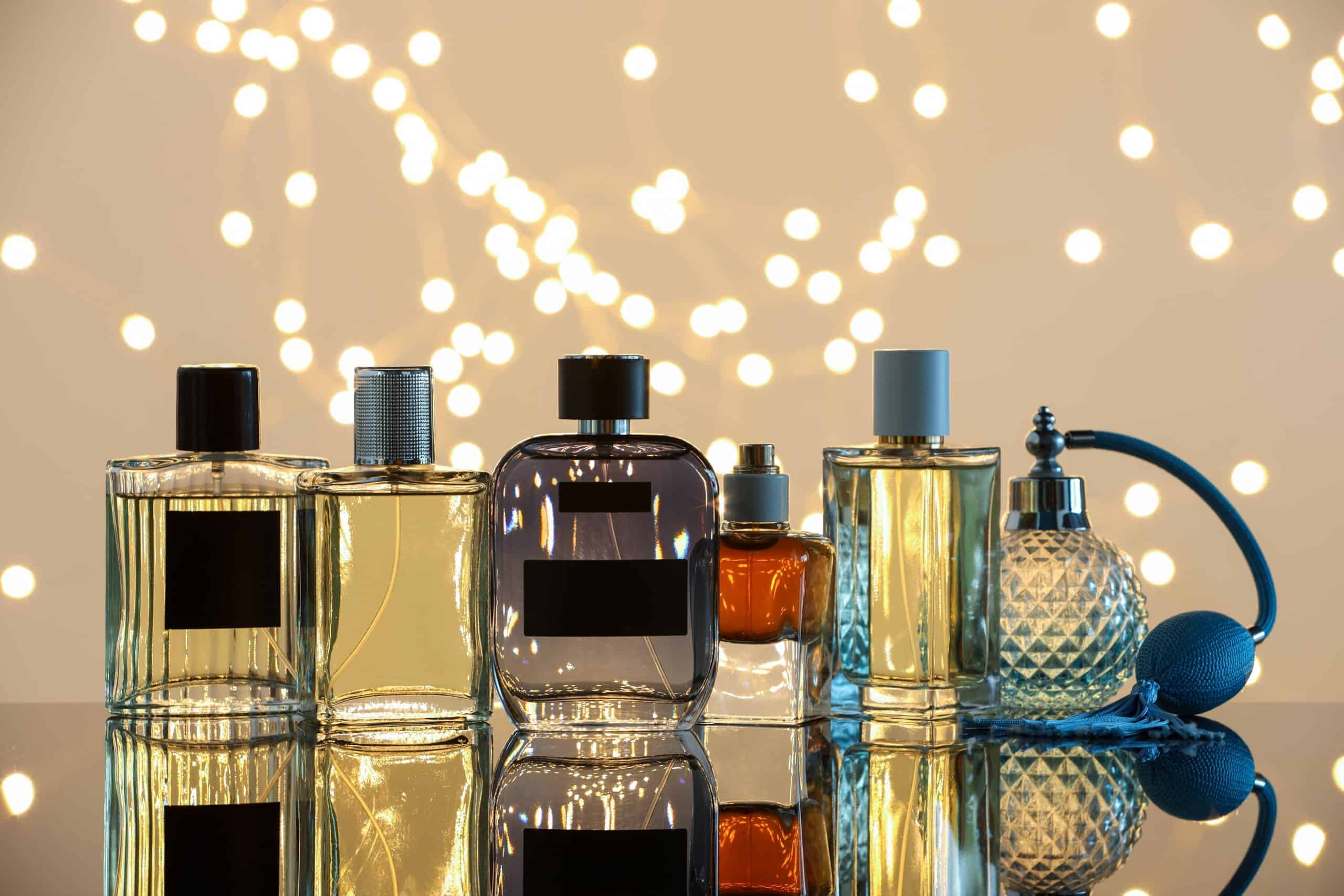 Different luxury perfumes on glass surface. Bokeh effect