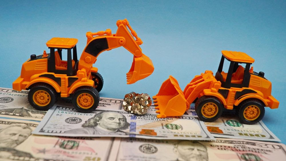 Dollar bills, excavators, and a piece of ore. Mining of rare earth metals.