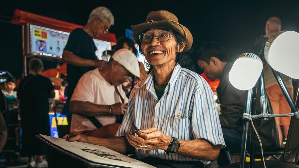 Happy asian male Vietnamese street artist paints on the street in Da Nang in Asia. Da Nang, Vietnam - November 29, 2024