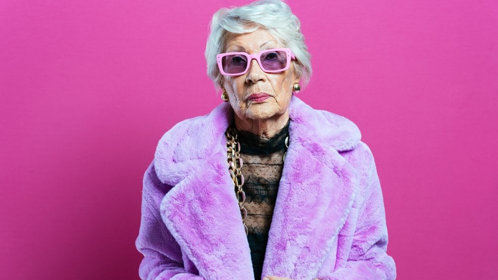 beautiful and elegant old influencer woman. Cool grandmother posing in studio wearing fashionable clothes. Happy senior lady celebrating and making party. Concept about seniority and lifestyle