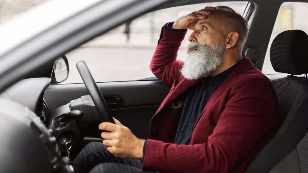 Shocked senior businessman having troubles on road, sitting in car