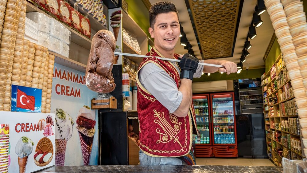 Istanbul, Turkey – October 09, 2024: Seller of “Dondurma” or Turkish ice cream preparing to do a spectacular show to customers who approach his shop.