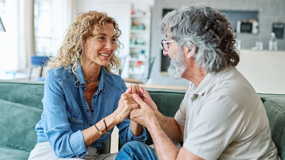 Portrait of a happy senior couple embracing talking at home