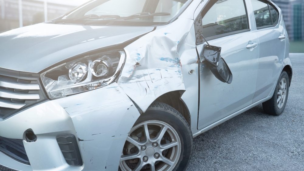 Front side view of a car with visible damage and dents after an accident. Vehicle crash, insurance claim, road safety, and car repair concept.