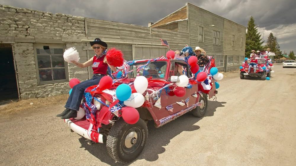 Woman sitting on the hood of a jeep decorated for the Fourth of July,in Lima Montana