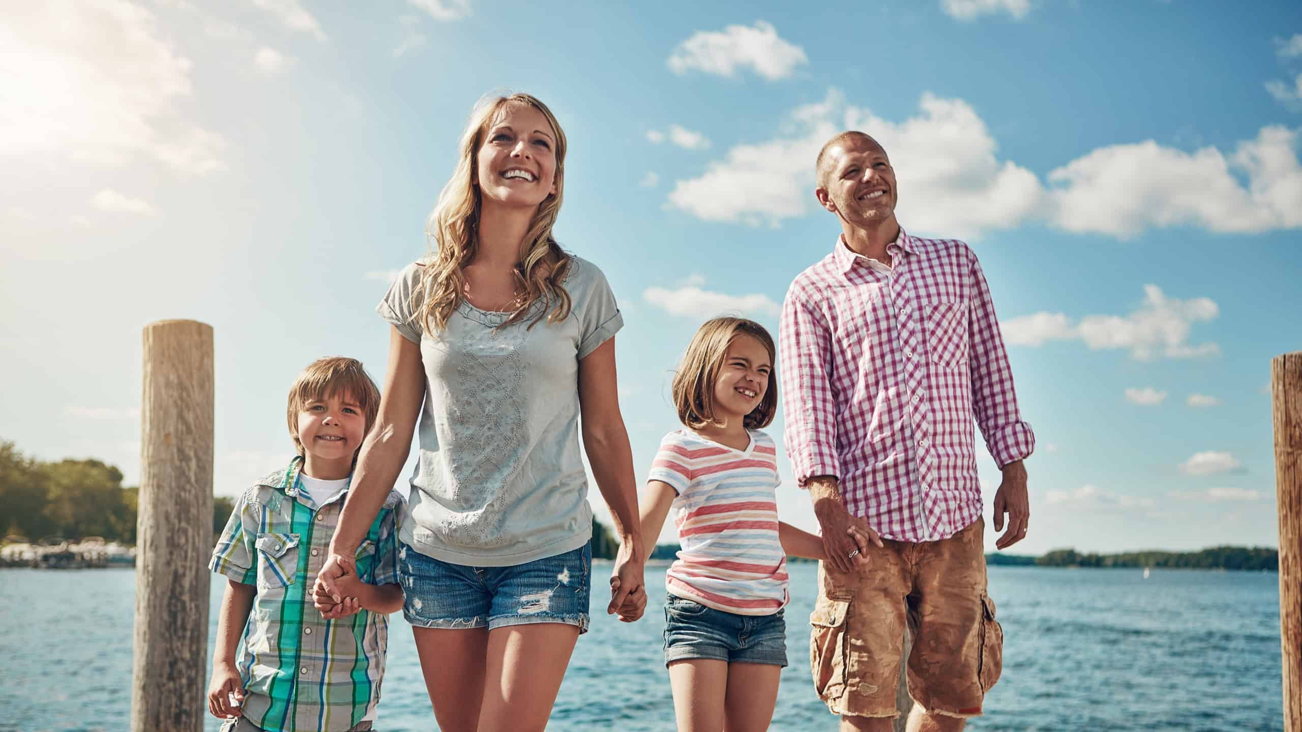 Lake, parents and kids with vacation, funny and bonding together with weekend break. River, family and mother with father, children and getaway trip with happiness, people and holding hands in Canada