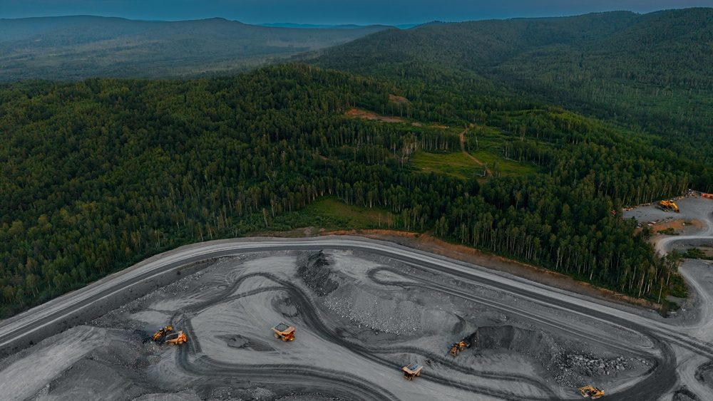 Aerial view of mining operation in forested hills at dusk.