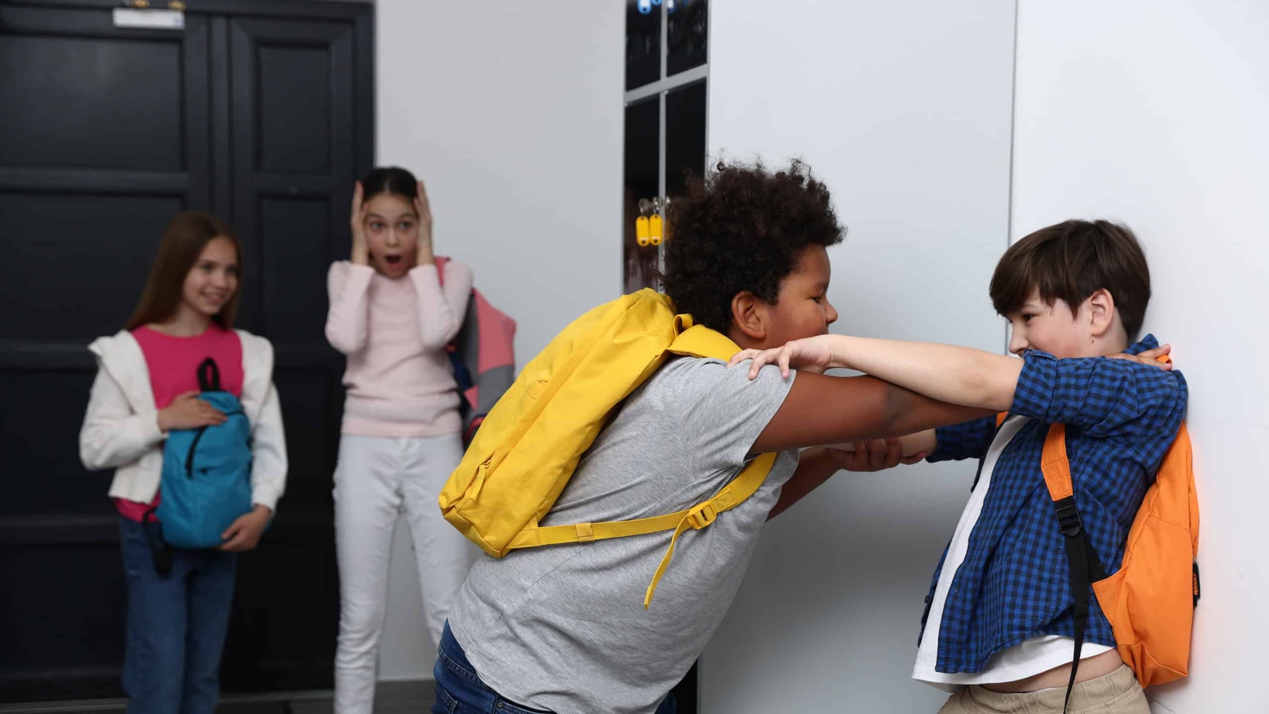 Bullying. Boy fighting with his African American classmate in school