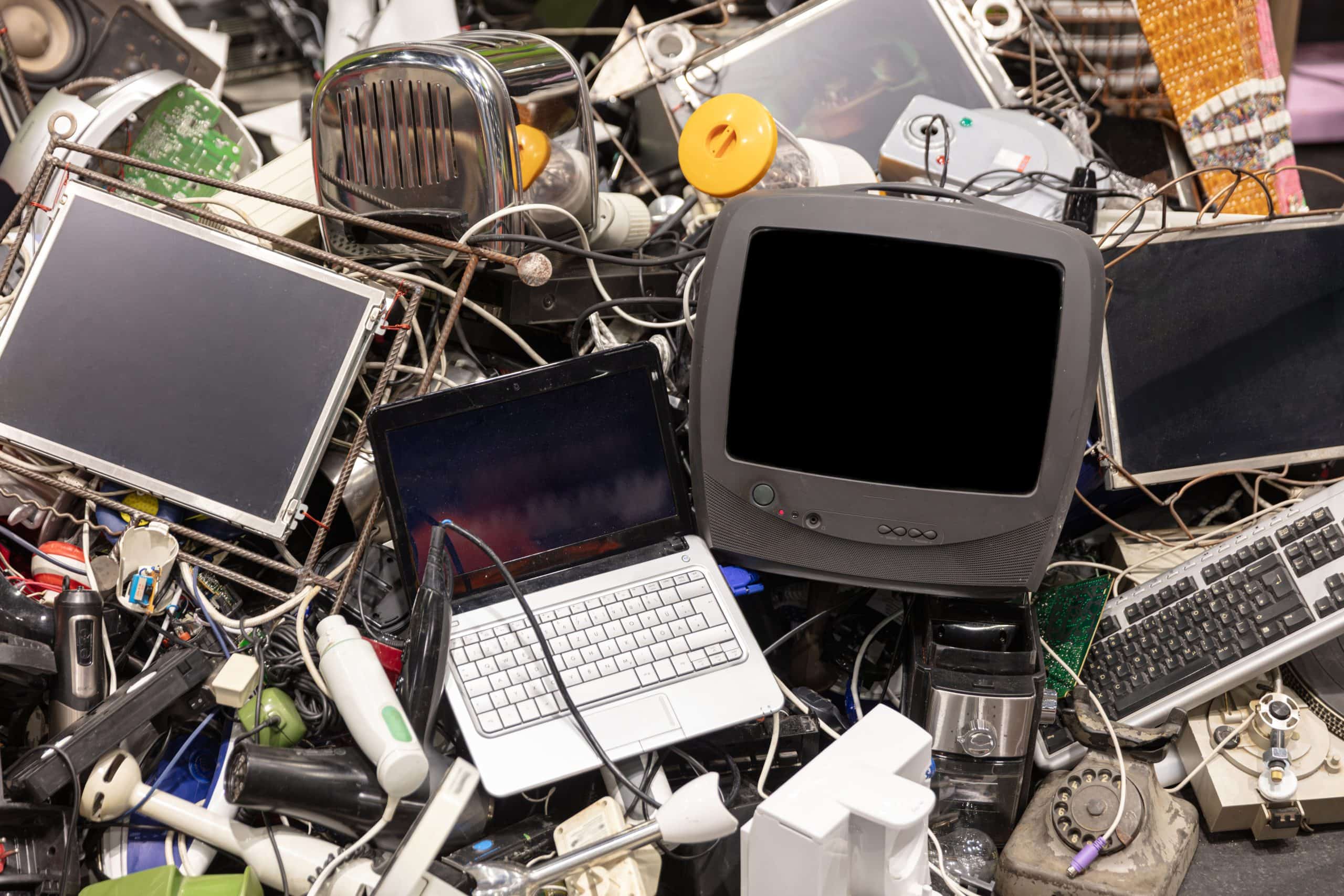 A pile of discarded electronic waste is shown including a laptop television keyboard and other obsolete devices. This image can be used for concepts related to recycling environmental issues and the disposal of electronic equipment.