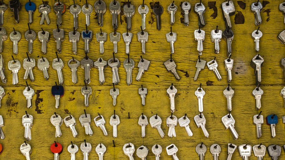 Marilia, SP, Brazil. April 16, 2026. A wide variety of metal key blanks hanging on hooks against a weathered yellow wooden board at a traditional local locksmith workshop. The image shows different types and sizes of keys ready to be cut for customers.
