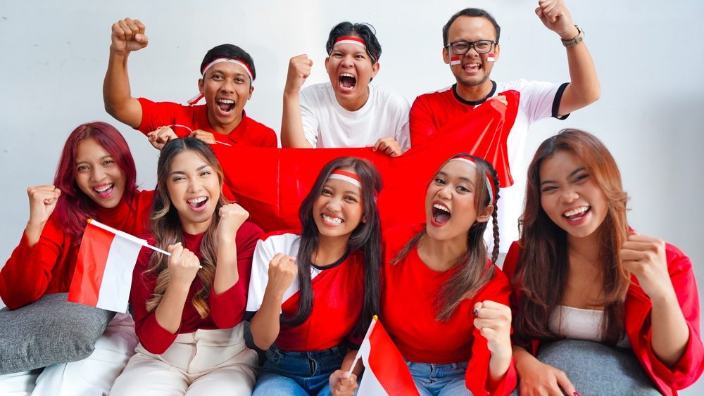 A group of Indonesian people holding their country flag and raising fists doing supporting hand gesture. Indonesia Independence Day concept.