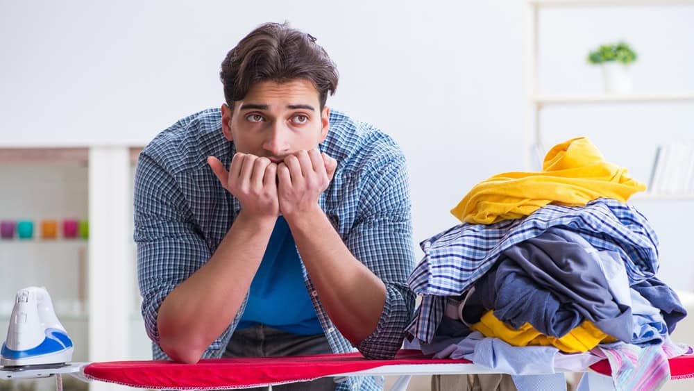 Young man husband doing clothing ironing at home