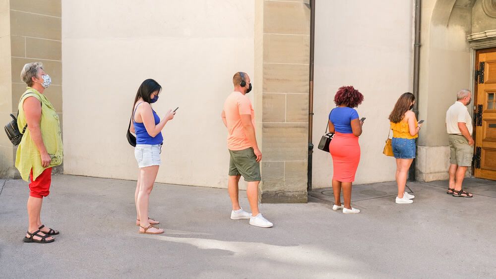 people in a queue with social distancing and wearing protective face masks - Concept of the coronavirus lifestyle and social distancing