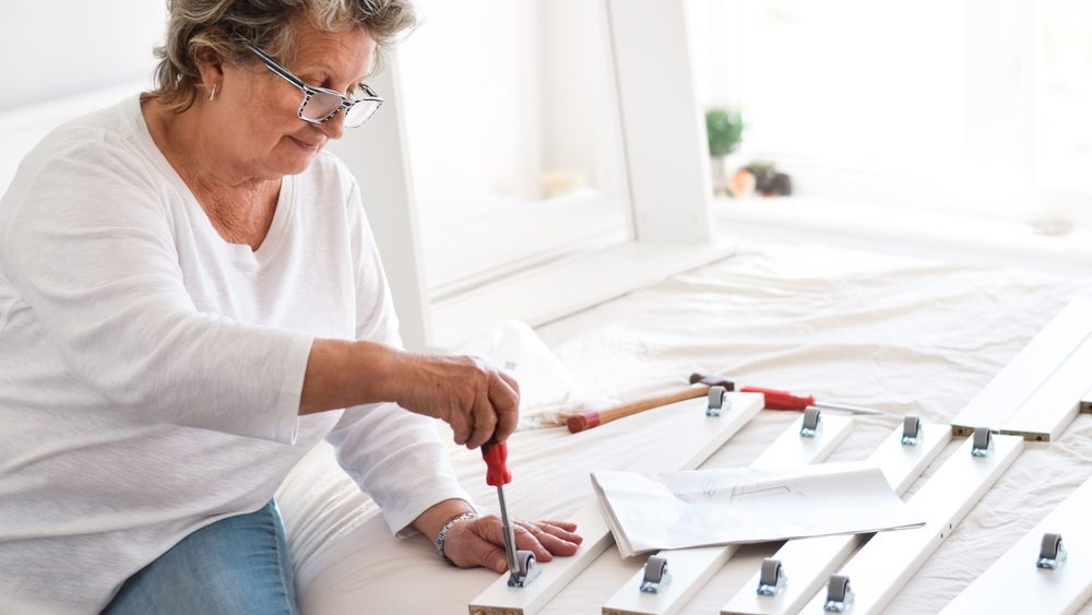 Senior woman using screwdriver to assemble furniture