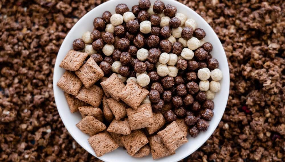 Top view of bowl with tasty cereal balls and puffs near granola