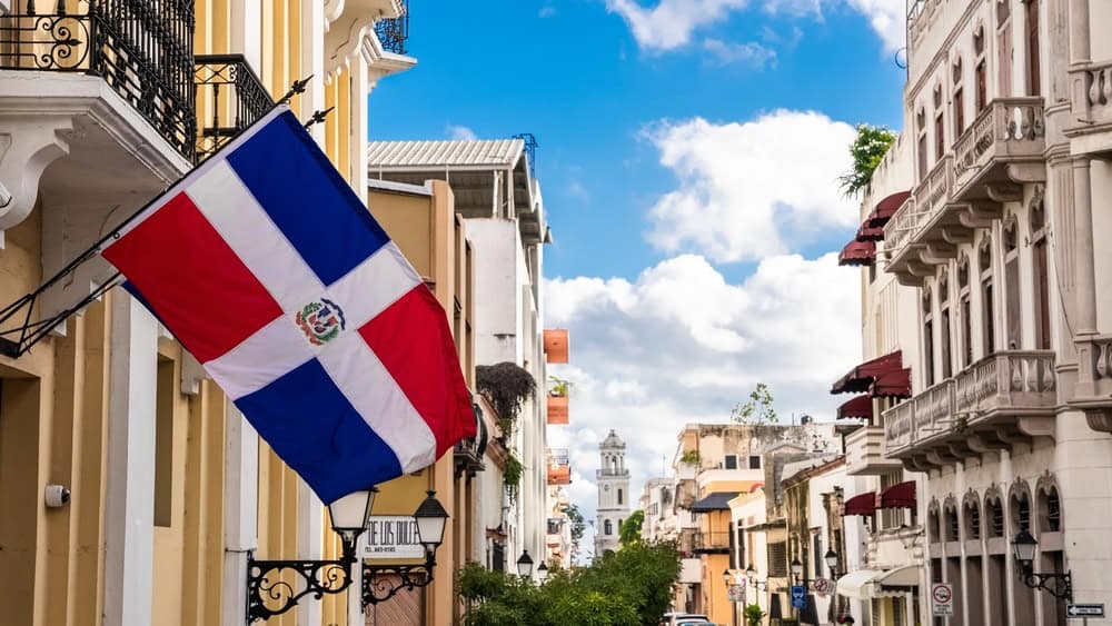 Dominican Republic, Santo Domingo - November 6, 2022: Flag of the Dominican Republic on the wall of a building in the colonial zone. Arzobispo Merino street. Popular tourist excursion. 