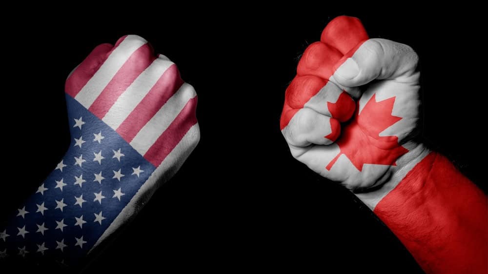 USA VS CANADA. Strong men hands painted country flags in fighting signal black background. Countries with social, economic, political, cultural, territorial, sports, financial conflicts.