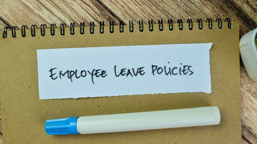 Concept of Employee Leave Policies write on sticky notes isolated on Wooden Table.