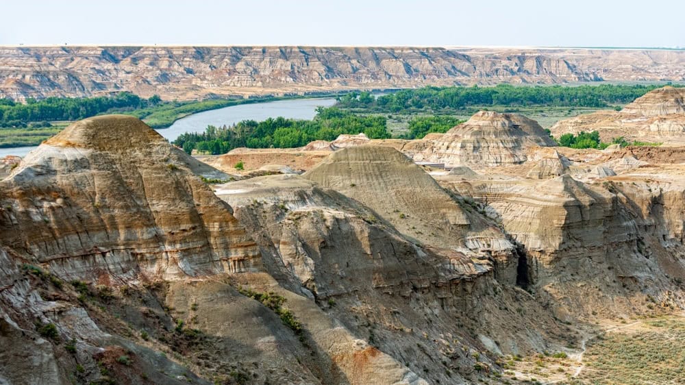 Dinosaur Provincial Park panorama: Vast badlands, rich with fossils, under endless skies. Mesmerizing hoodoos, dinosaurs' ancient home. Nature's masterpiece!