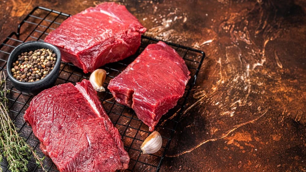 Raw Wild Game Meat of Venison dear ready for cooking. Dark background. Top view. Copy space.