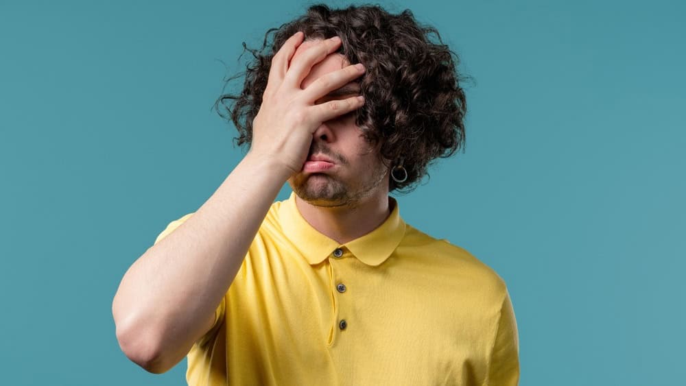 Worried man doing panic despair gesture, like no, I forgot. Disappointed guy feeling sorrow, regret, drama, failure, problems on blue background. High quality
