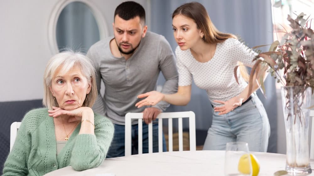 Portrait of annoyed stressed senior woman ignoring her adult children scolding her at home