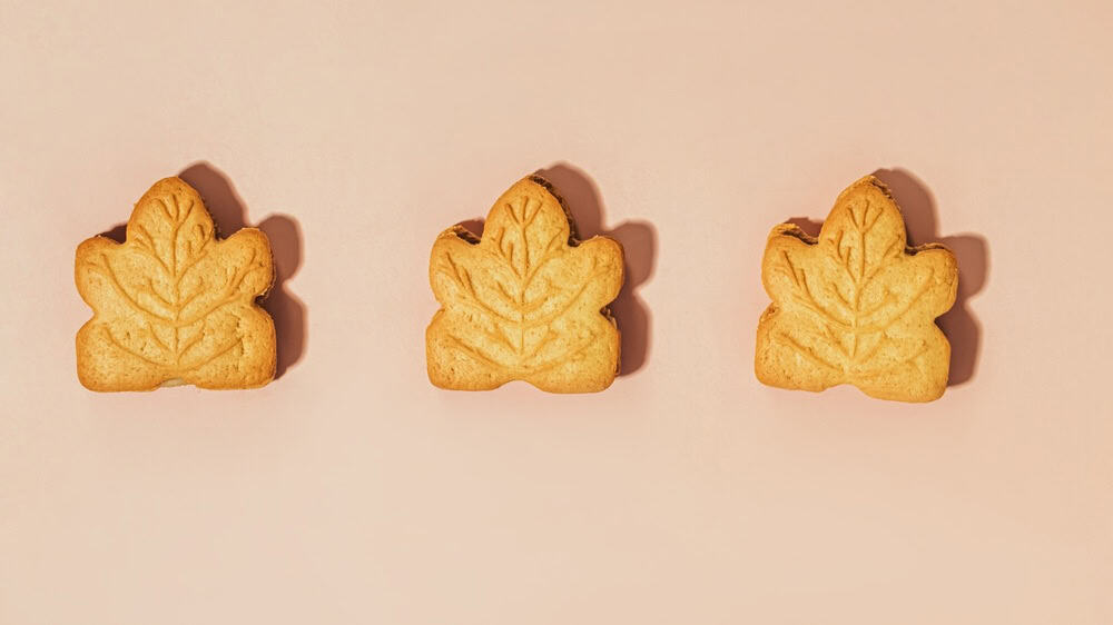 Sweet leaf-shaped cookies arranged in a row on a soft pastel background in natural light