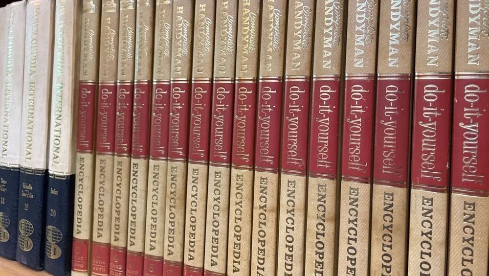 Yogyakarta, Indonesia - December 15 2024: A close-up view of a collection of vintage "Complete Handyman Encyclopedia" books with their spines lined up, showcasing the aged paper and gold lettering.