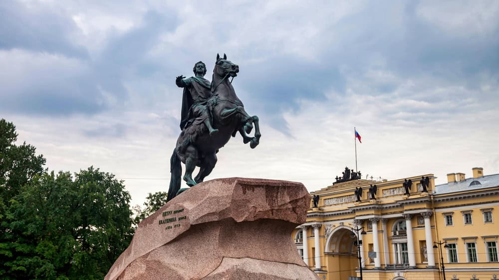 St Petersburg, Russia - May 1 2025: The powerful equestrian statue of Peter the Great stands tall in Saint Petersburg, surrounded by lush greenery and historical architecture under a cloudy sky.