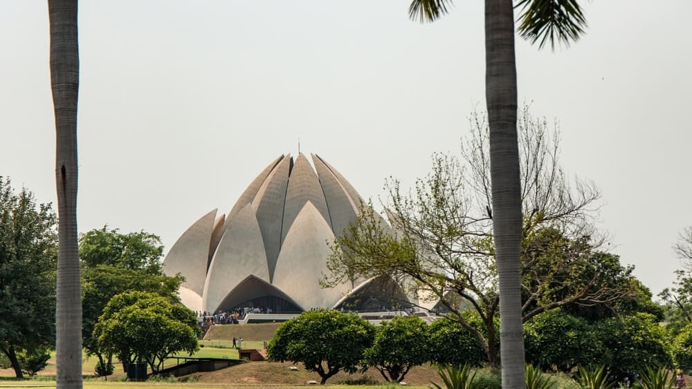 08-08-2025, Delhi, Lotus Temple, a Baháʼí House of Worship, rises majestically among lush greenery, its lotus-shaped design blending beautifully with surrounding palm trees in New Delhi, India