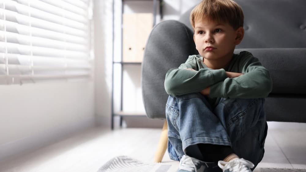 Child in danger. Lonely little boy sitting on floor at home, space for text