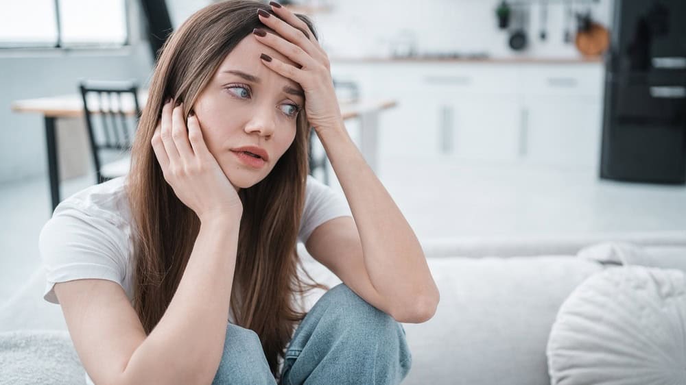 Female having depression sitting alone in bedroom corner. Young woman has headache, unhappy emotion, anxiety, solitude despairing mental health financial problems, emotional stress