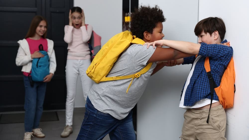 Bullying. Boy fighting with his African American classmate in school
