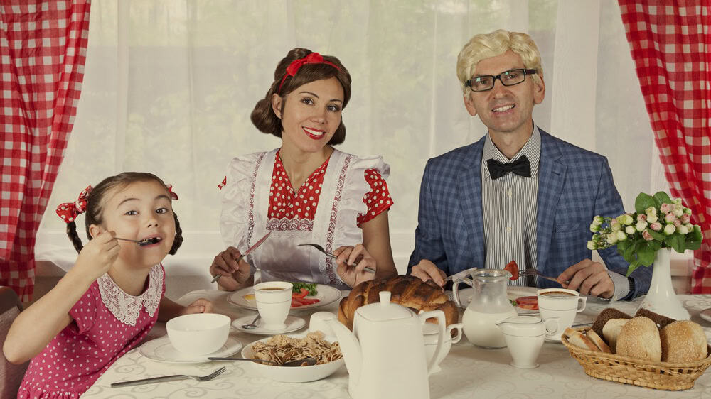 Retro styled family sitting at the table while have breakfast. Monochrome, grunge textures, intentional styled to the 1900s