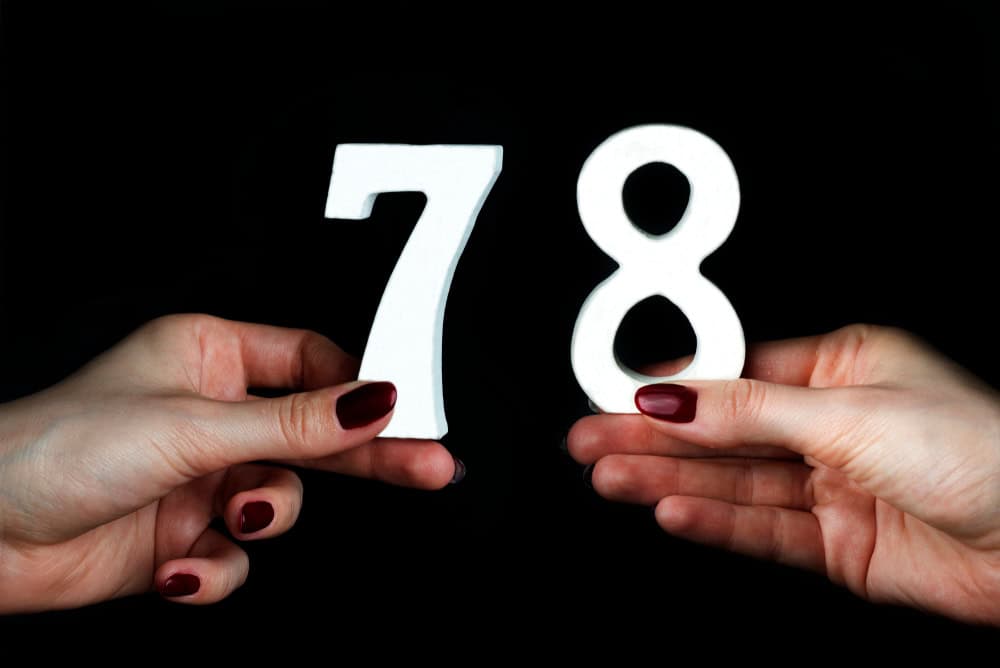 On a black background, female hand with numbers seventy-eight.