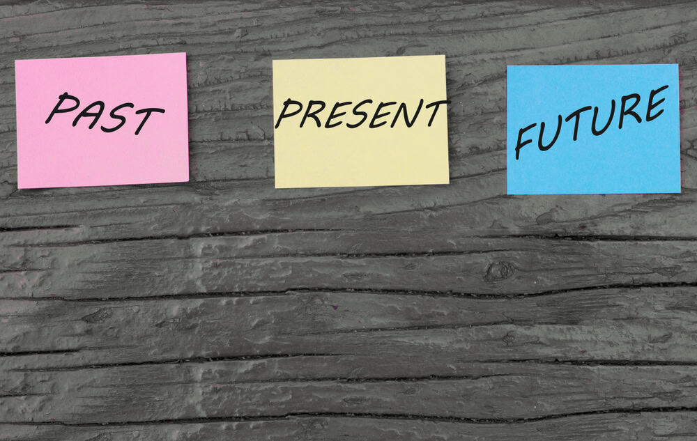 Inscriptions Present, past and future on multi-colored office stickers. adoption of planning, choice, motivation. business concept. Red wooden background. Copy space
