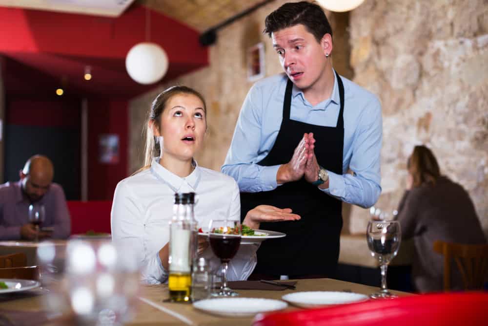 Female guest expressing displeasure with food talking to excusing waiter