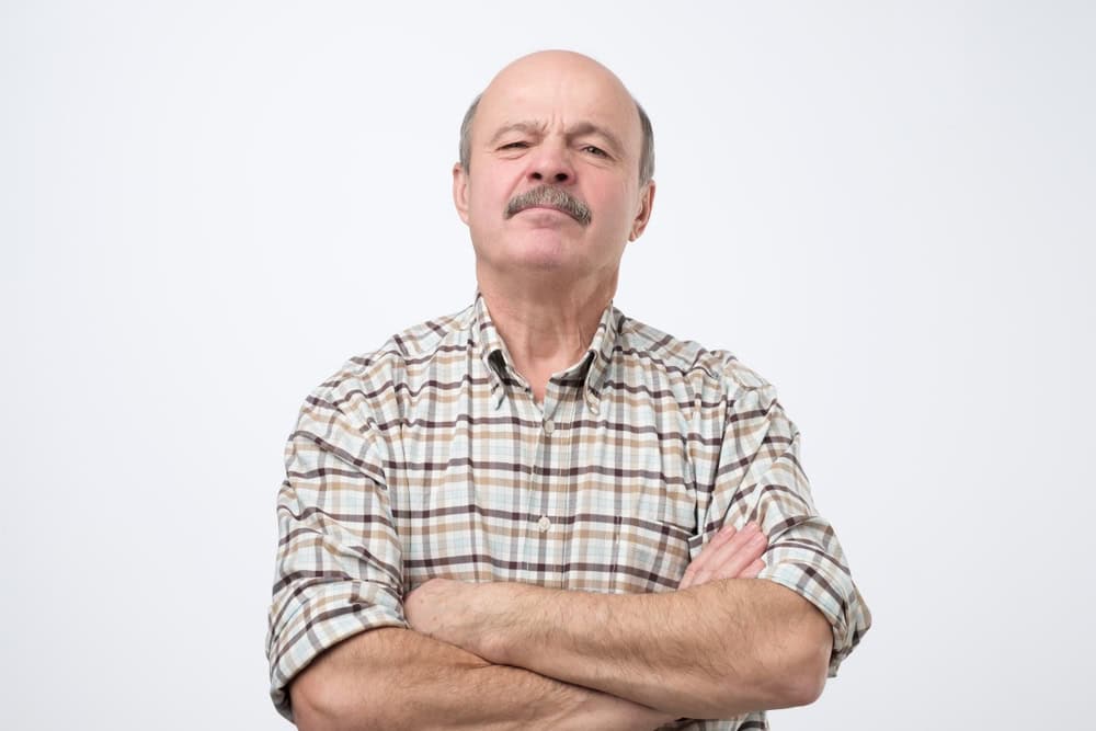 Portrait of selfish senior man crossing hands on his chest. He is jealous for someone success.