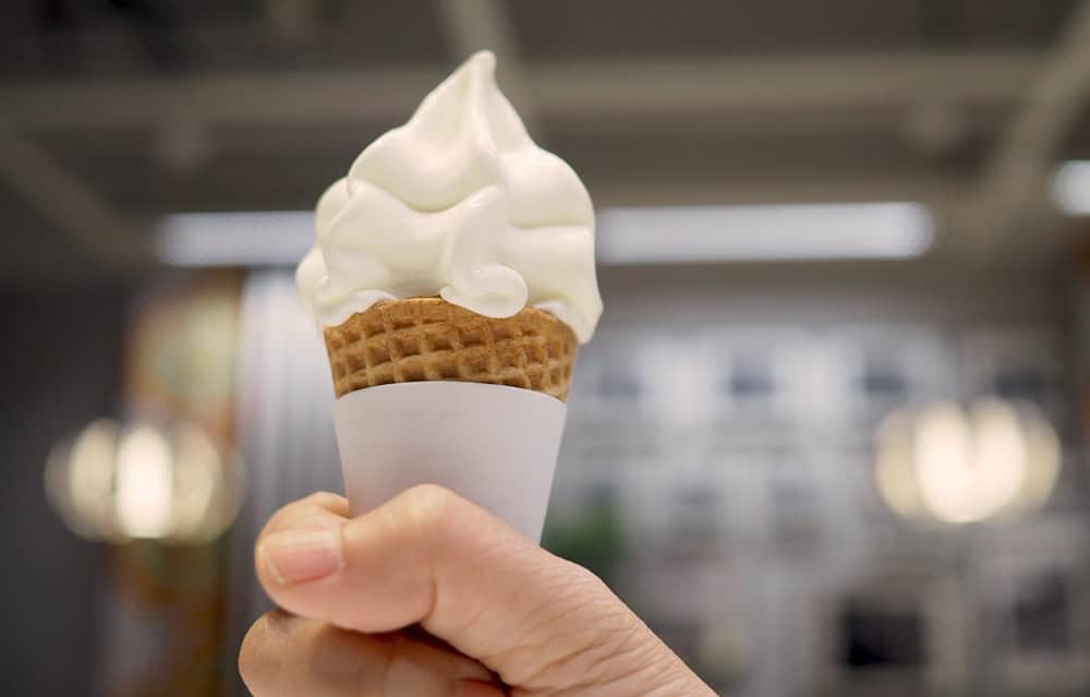 Right Hand is holding soft cream or soft serve ice cream cone.