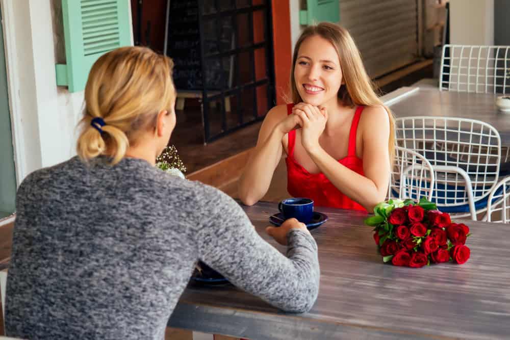 surprised blonde woman and handsome blond man at restaurant.happy couple romantic date, celebrating valentine day male model give red rose to his girl