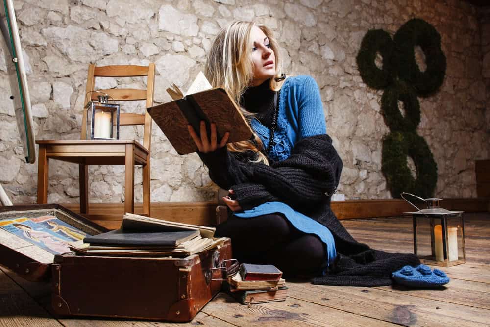 Elegant beautiful woman with books and vintage suitcases in country house