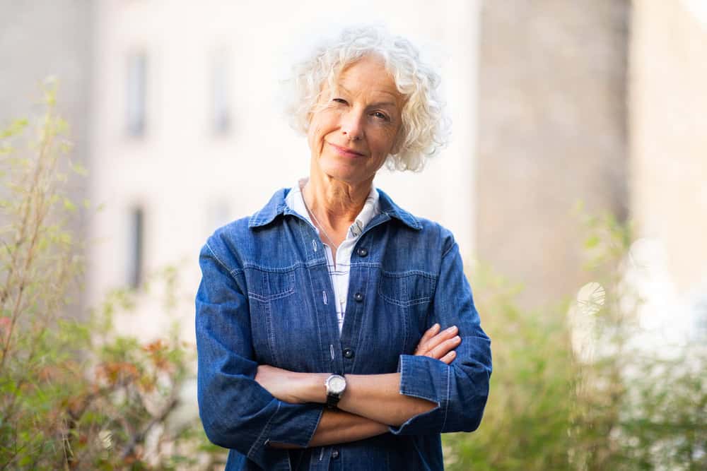 Portrait attractive older woman posing outside with arms crossed